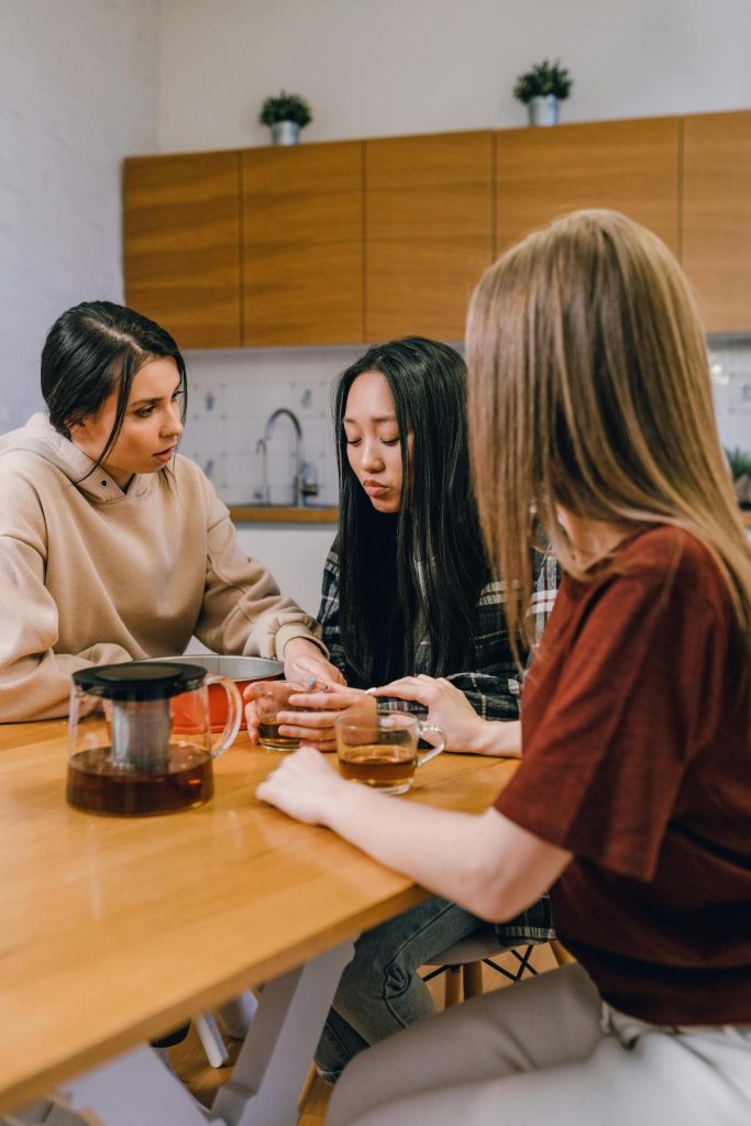three young women discuss an upsetting breakup as they comfort their friend who is looking sad