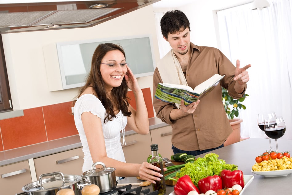 Happy couple cook in kitchen with cookbook