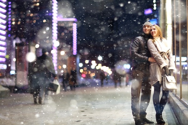 Love man and woman embracing outdoors winter snowfall